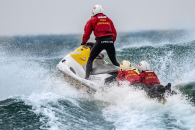 RNLI lifeguards on a jet powered watercraft heading over the surf