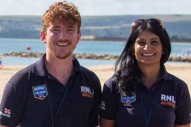 Face to face fundraisers on a beach wearing RNLI polo shirts